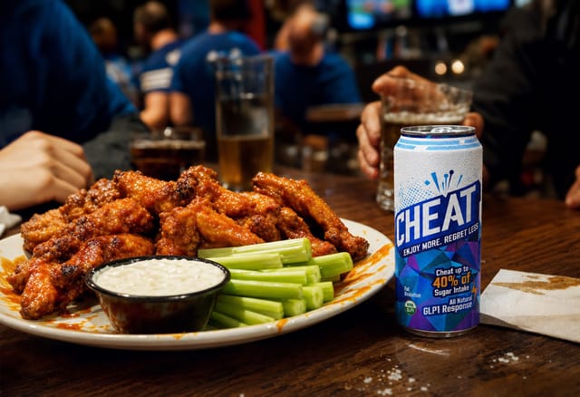 A platter of buffalo wings with blue cheese and celery, sauce smears, sports bar table