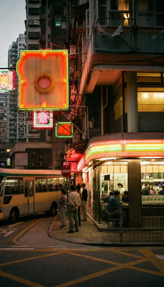 Hong Kong street with dense hanging neon signs, a cha chaan teng diner glowing, minibus passing