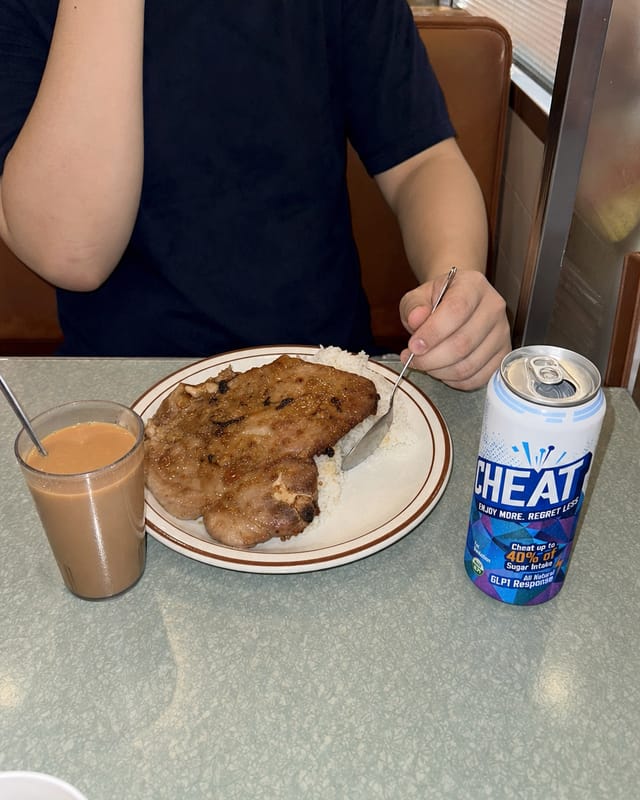 Hong Kong diner booth, a plate of baked pork chop rice and milk tea, laminate table, harsh light