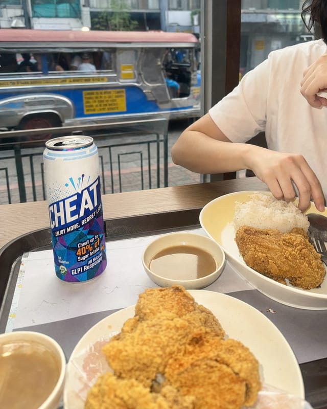 Manila fast-food table with fried chicken, rice and gravy, jeepney visible outside the window, bright