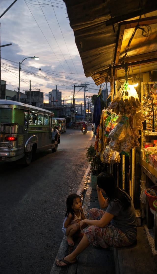 Manila street at dusk, jeepneys, sari-sari store front, hanging snack packets, warm light