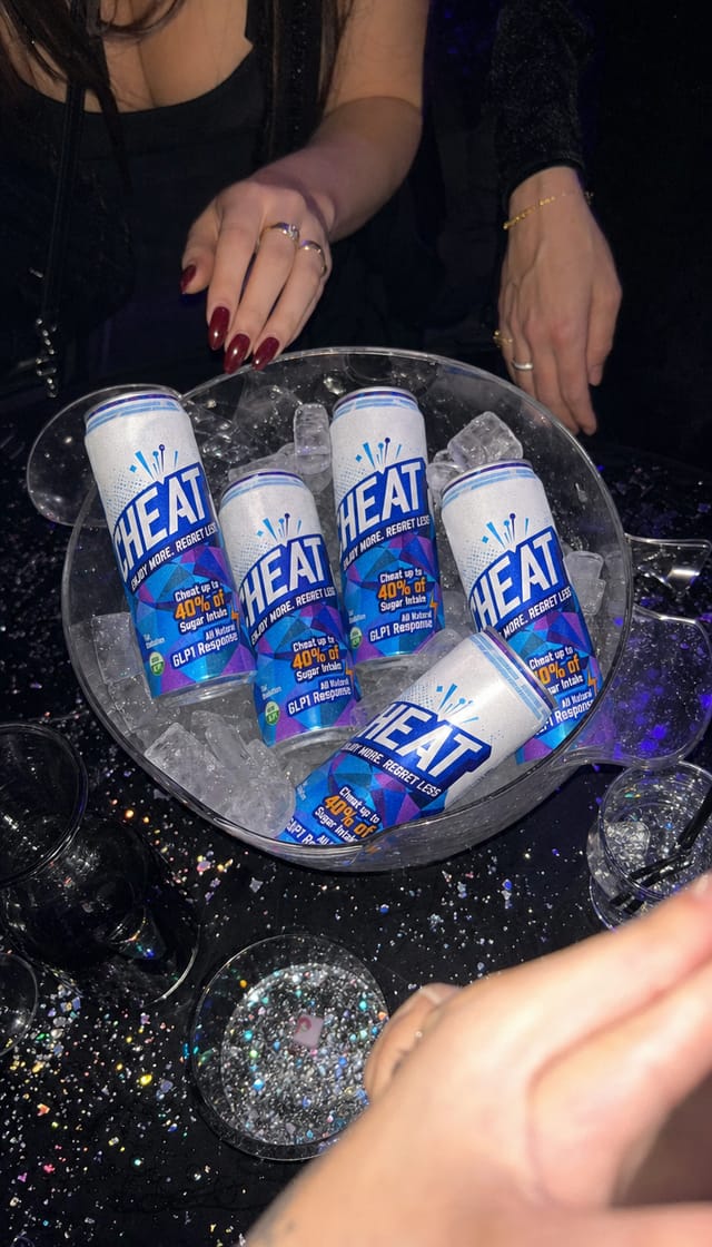 A nightclub booth table with an ice bucket, strobe light frozen by flash, hands, glitter