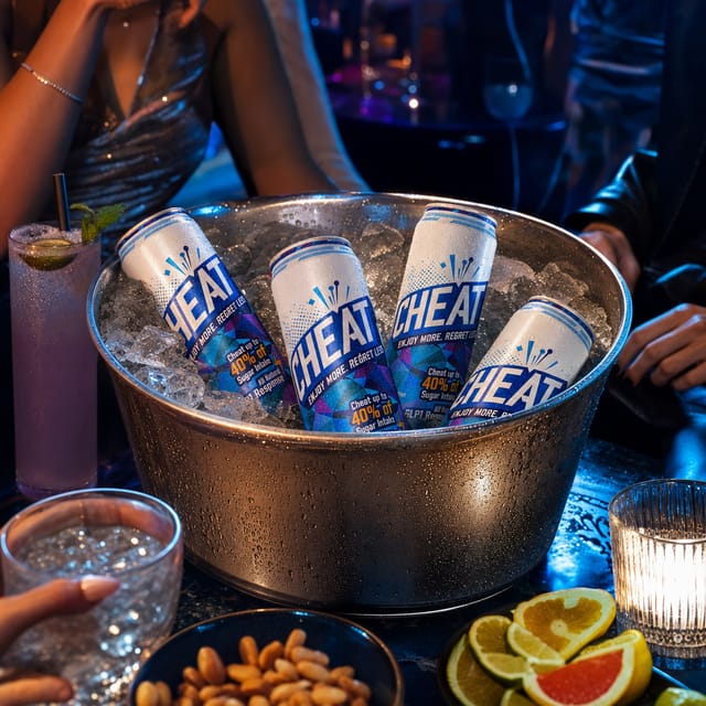 A metal ice bucket packed with ice on a nightclub table, colored light, condensation